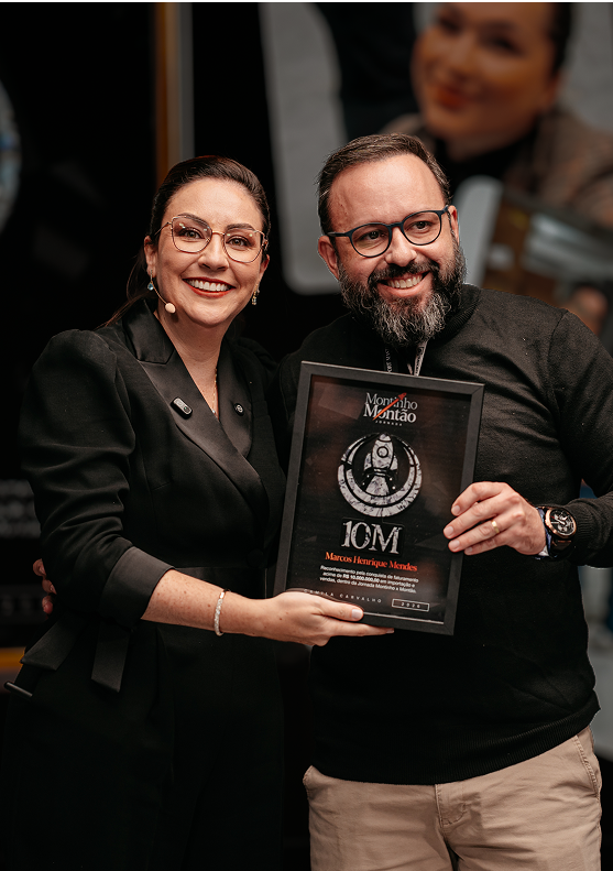 Camila e Marcos comemorando com a placa de 10 milhões no palco
